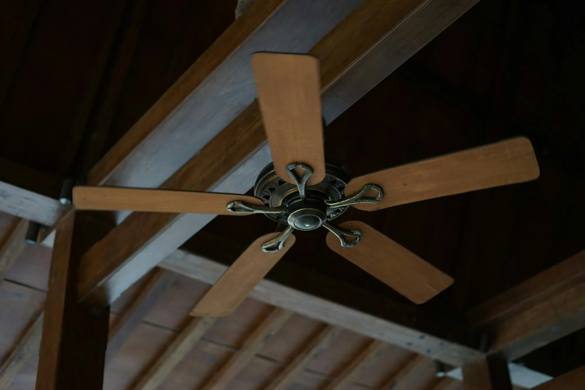 Ceiling fan with wooden blades mounted on a vaulted ceiling
