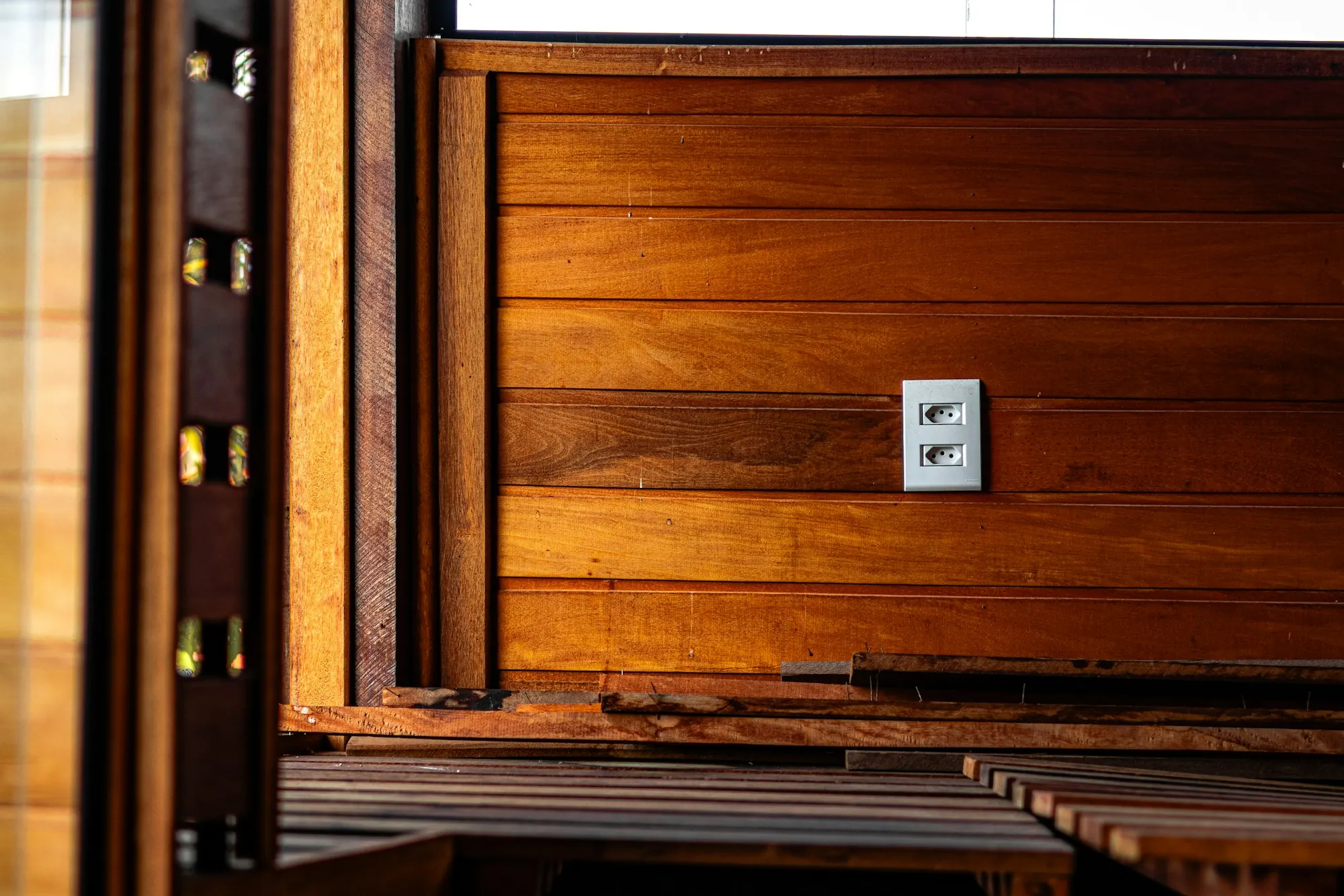 A white electrical outlet on a warm wooden wall