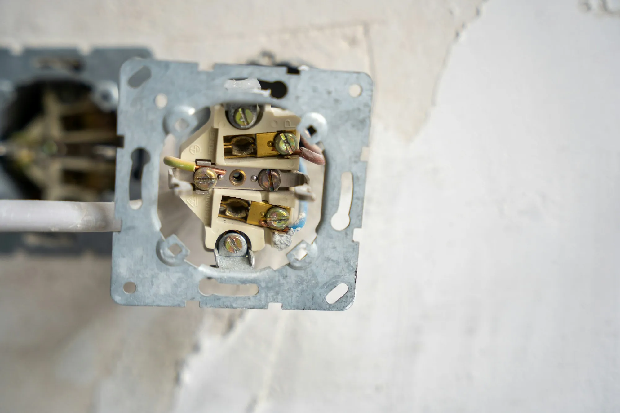 An outlet pulled from the wall with its wiring exposed